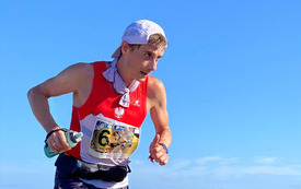 Mężczyzna w stroju sportowym biegnie z wysiłkiem w g&oacute;rach