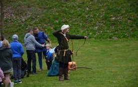 chłopak w stroju z epoki po oddaniu strzału, za nim osoby