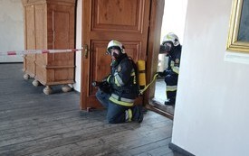 Strażacy ubrani w kombinezony i maski przed wejściem na zadymione piętro zamku
