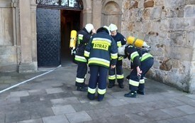 Grupka strażak&oacute;w naradza się przed wejściem na zamek