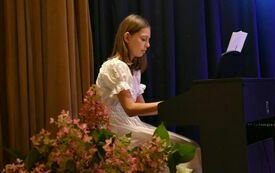 dziewczynka w białej sukience gra na pianinie