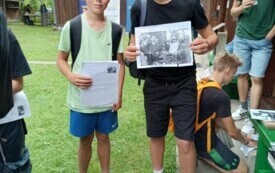 chłopcy przed budynkiem z fotografią w dłoni, inne osoby
