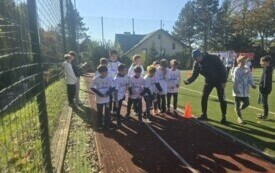 chłopcy stoją na lini startu, w tle drzewa inne budynki