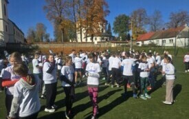 zawodnicy na boisku, rozmawiają, w tle inne budynki, drzewa