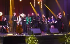 muzycy z r&oacute;żami w dłoniach słuchają podziękowań burmistrza Nowego Wiśnicza