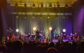 ujęcie na scenę z dala oświetloną kolorowymi reflektorami, na scenie muzycy i soiliści