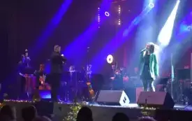 kolorowa scena z muzykami i śpiewającą solistką