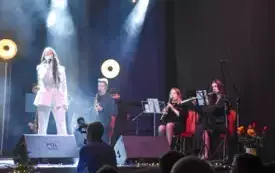 ubrana na biało solistka śpiewa, w tle flecistki