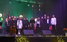 ch&oacute;r dziecięcy z nauczycielką stoją na scenie