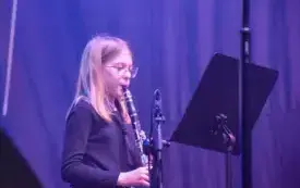 dziewczynka z blond włosami gra na klarnecie