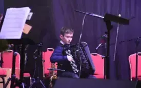 chłopiec na scenie gra na akordeonie