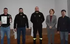 strażak z pucharem i dyplomem oraz wręczający