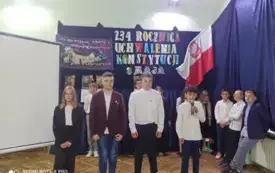dzieci występują na akademii w tle ścianka z flagą Polski