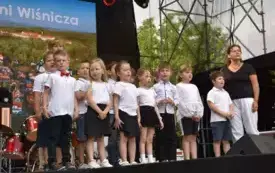 grupa dzieci śpiewa na scenie piosenkę