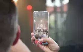 dłoń trzyma kom&oacute;rkę nagrywającą występ muzyka