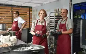 saomrządowcy w fartuchach kuharskich podają ludziom jedzenie