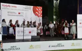 zesp&oacute;ł w strojach ludowych trzyma baner z nazwą projektu