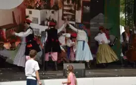 zesp&oacute;ł w strojach ludowych tańczy na scenie