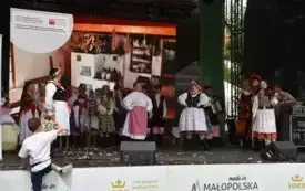 zesp&oacute;ł w strojach ludowych tańczy na scenie