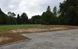 utwardzony parking, drzewa w oddali