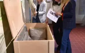 pracownicy muzeum stoją z dokumentami przy drewnianej skrzyni