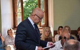 radny odczytuje uchwałę, inne osoby w tle