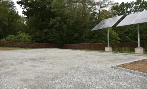 utwardzony parking, po prawej solary, drzewa w oddali