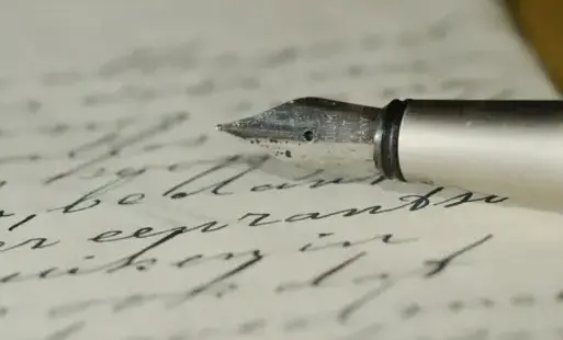 pióro leżące na zapisanej kartce papieru