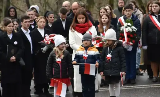 dzieci z chorągiewkami, w tle inne osoby