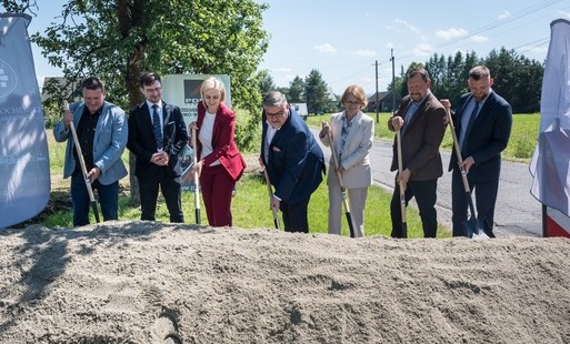 osoby z łopatami, hałda ziemi, drzewa w tle